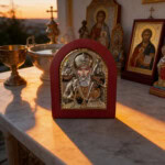 Icône de Saint Nicolas avec cadre rouge et décorations religieuses.