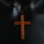Croix en bois suspendue avec cordon noir, symbole religieux.